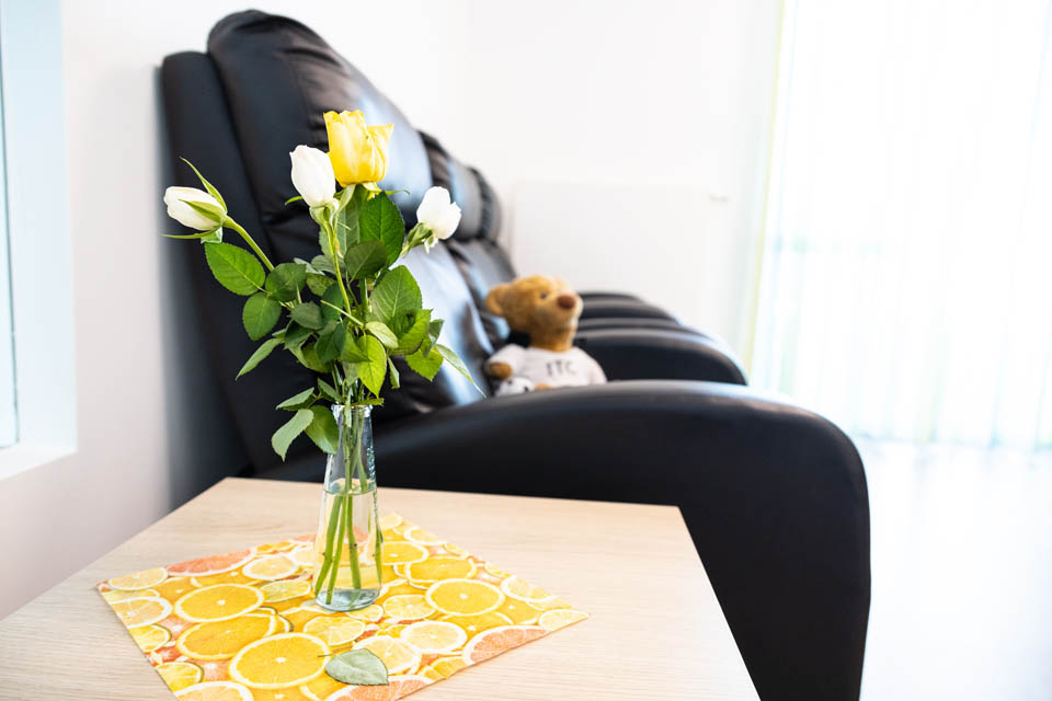 Im Ruheraum der BRK-Tagesplfege Gangkofen befinden sich bequeme schwarze Ledersessel. Neben den Sesseln ist ein Beistelltisch mit einer Blumenvase und gelb-weißen Blumen