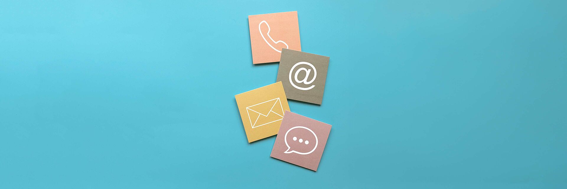 In der Mitte des Bildes sind 4 Symbole übereinander angeordnet: Telefonhörer, ein @-Zeichen, ein Briefumschlag und eine Sprechblase. Der Hintergrund ist hellblau.